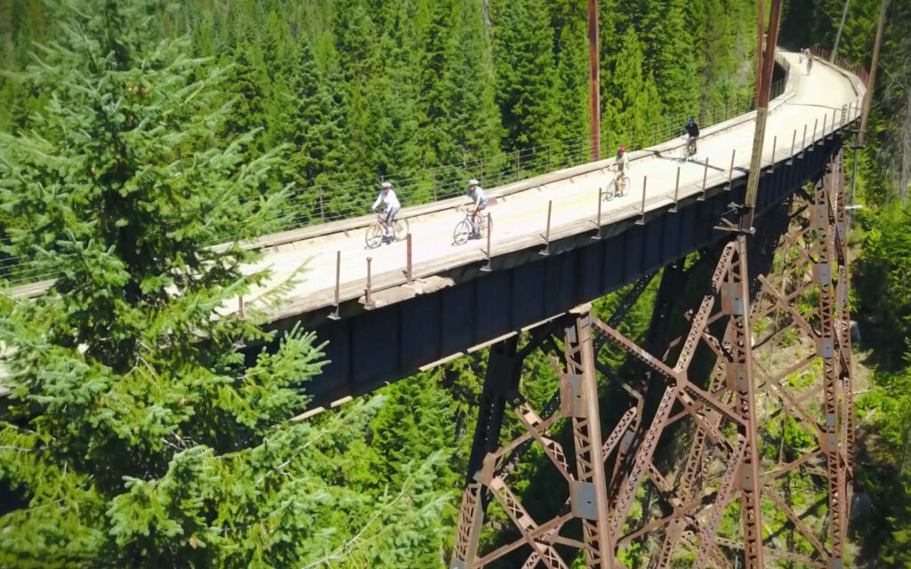 Cyclist riding across a wooden trestle on the Route of the Hiawatha trail